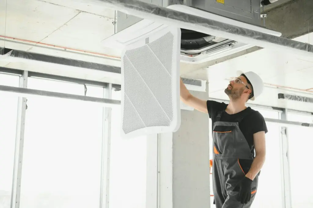 Worker repairing ceiling air conditioning unit